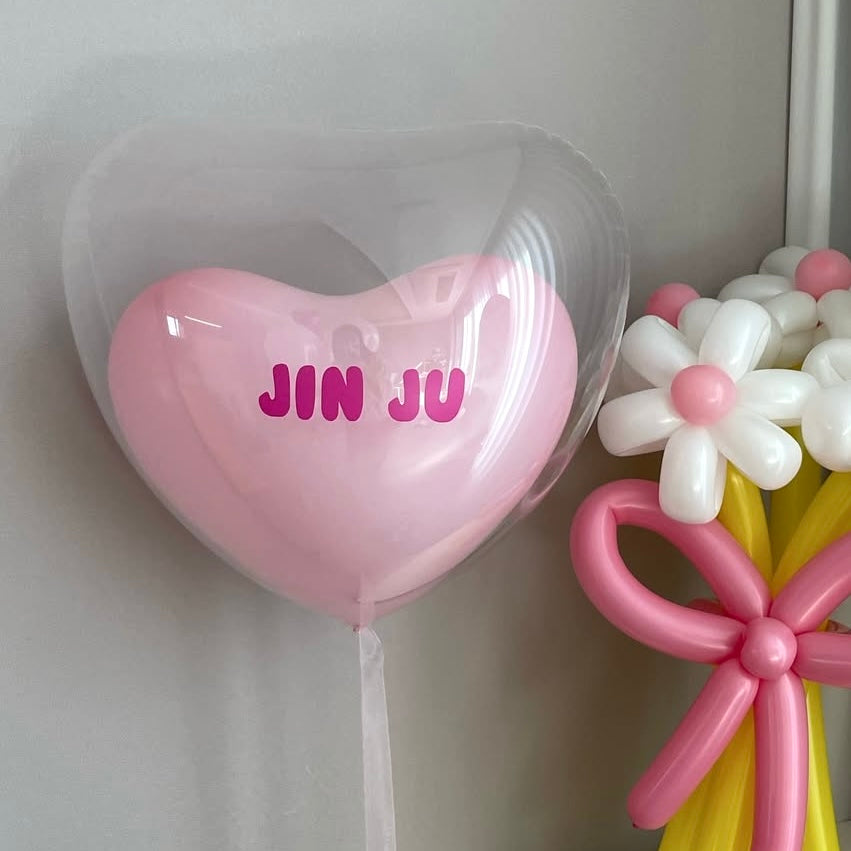 Ballon cœur transparent avec ballon rose à l'intérieur et prénom personnalisé en vinyle autocollant sur ballon, idéal pour anniversaire ou mariage.